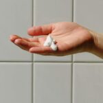 person with soap foam on hand with ceramic tile background