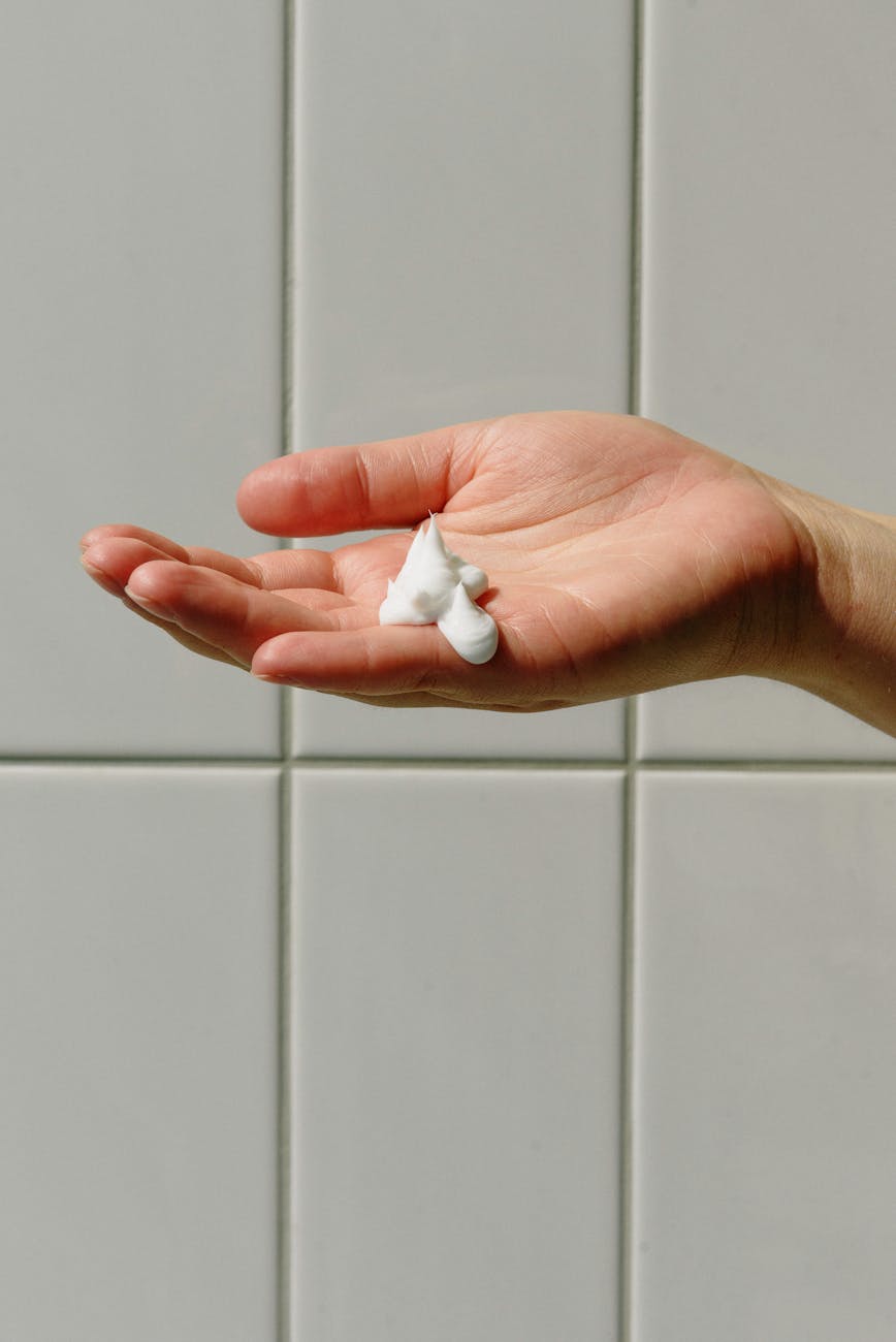 person with soap foam on hand with ceramic tile background