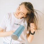 woman in white shirt drying her hair